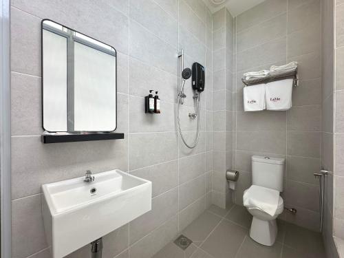 a bathroom with a sink and a toilet and a mirror at La Vie Hotel Juru in Simpang Ampat