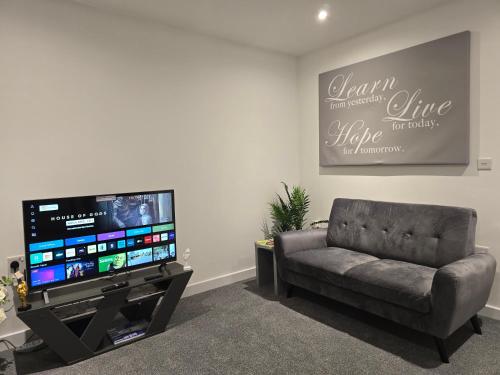 a living room with a couch and a flat screen tv at Well-Preserved 2 Bedroom Flat Apartment Around Ricoh Arena-Coventry City FC in Longford