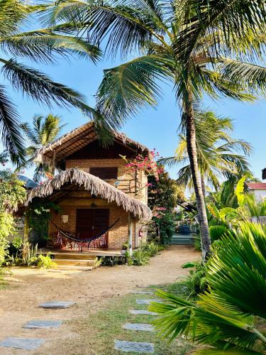 a house with a straw roof and a palm tree at Pousada kaz'oca in Icaraí