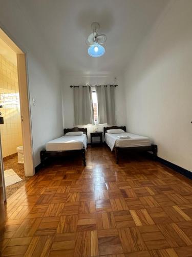 Cette chambre comprend 3 lits et du parquet. dans l'établissement Hotel Itapetininga, à Itapetininga