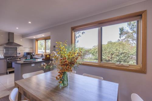 Una cocina con una mesa con un jarrón de flores encima. en JoY's Guesthouse, en Romsey