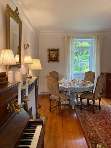 un salon avec une table et un piano dans l'établissement Roulage Ferme 18ème Normandie Plage, à Longueville