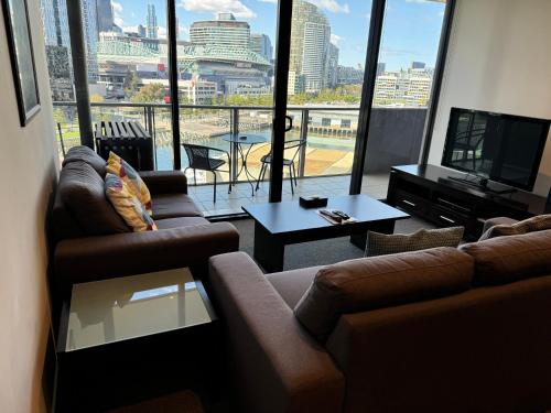 a living room with couches and a view of a city at AKOM AT Docklands in Melbourne