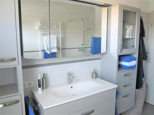 a white bathroom with a sink and a mirror at Ferienwohnung im Kirschfeld - 5* in Kues