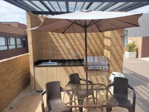 a table and chairs under an umbrella on a patio at Moderno Apartamento Chapinero Bogota in Bogotá