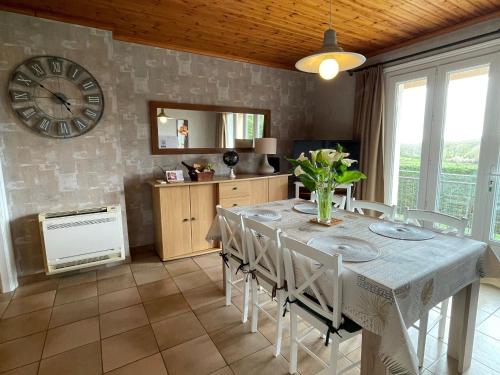 une salle à manger avec une table et une horloge au mur dans l'établissement Gîte calme entre Pornic et Nantes avec jardin, terrasse, jeux, WiFi, et équipements pour enfants - FR-1-306-1022, à Saint-Hilaire-de-Chaléons