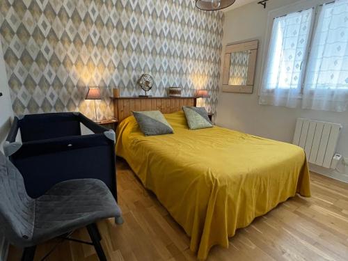 une chambre avec un lit jaune et une chaise dans l'établissement Gîte calme entre Pornic et Nantes avec jardin, terrasse, jeux, WiFi, et équipements pour enfants - FR-1-306-1022, à Saint-Hilaire-de-Chaléons