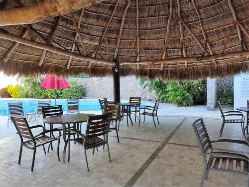a group of tables and chairs under a straw umbrella at Cozy family house with pool in Puerto Vallarta