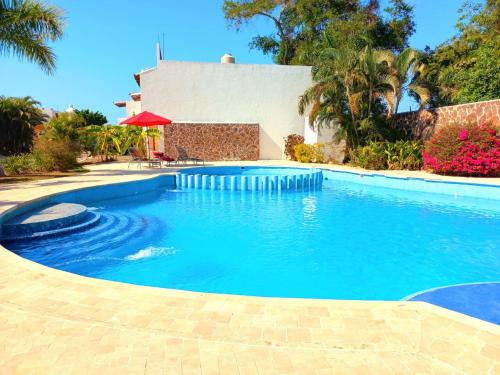 a swimming pool with blue water in front of a house at Cozy family house with pool in Puerto Vallarta