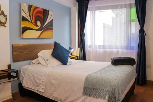 a bedroom with a bed with blue walls and a window at Casa El Retiro - Villa de Leyva in Villa de Leyva