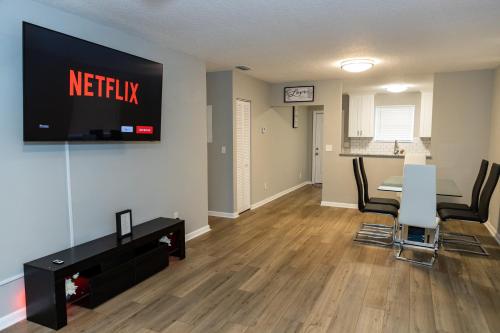 a living room with a table and a television on a wall at Cozy and Modern Vacation Home in Hallandale Beach
