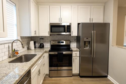 a kitchen with stainless steel appliances and white cabinets at Cozy and Modern Vacation Home in Hallandale Beach