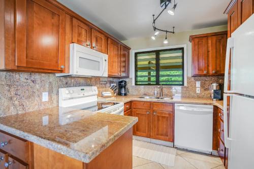 a kitchen with wooden cabinets and white appliances at Ocean View at Kaha Lani 310 in Lihue