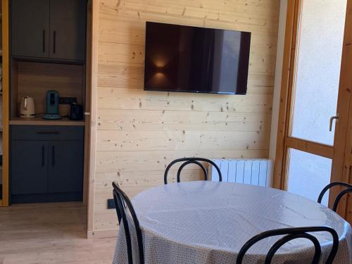 une salle à manger avec une table et une télévision murale dans l'établissement Charmant appart 2P cabine, rénové, balcon, parking gratuit, pied des pistes - FR-1-755-22, à Aime La Plagne