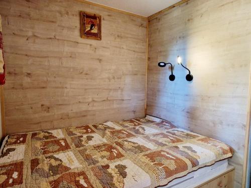 a bedroom with a bed with a wooden wall at Charmant T2 avec terrasse, proche pistes, parking gratuit - FR-1-755-21 in Aime La Plagne