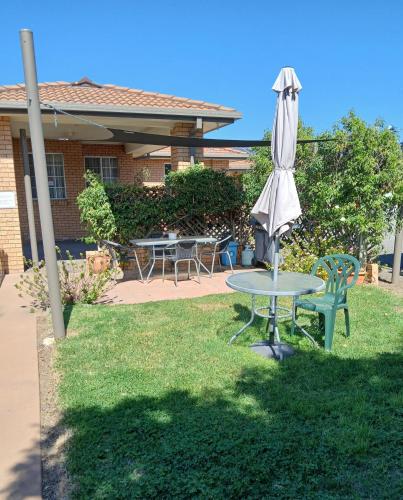 a table and an umbrella in a yard at Aaron Inn Motel in Narrabri