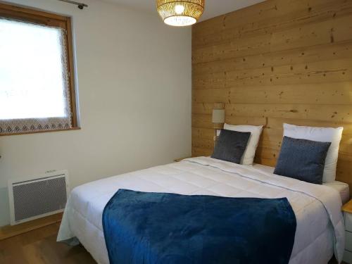 une chambre avec un grand lit avec un mur en bois dans l'établissement Appartement cosy 4* pied de pistes avec balcon et parking à Valmorel - FR-1-356-502, à Valmorel