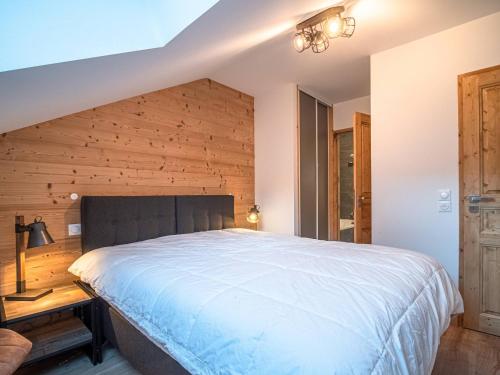 - une chambre avec un grand lit et un mur en bois dans l'établissement Superbe Appartement Pied de Pistes pour 7 pers avec Balcon, WIFI et Parking - FR-1-356-495, à Valmorel