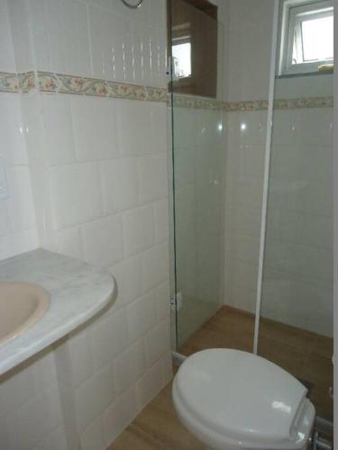 a white bathroom with a toilet and a sink at Apartamento aconchegante a 1 km da principal praia de Cabo Frio in Škorak