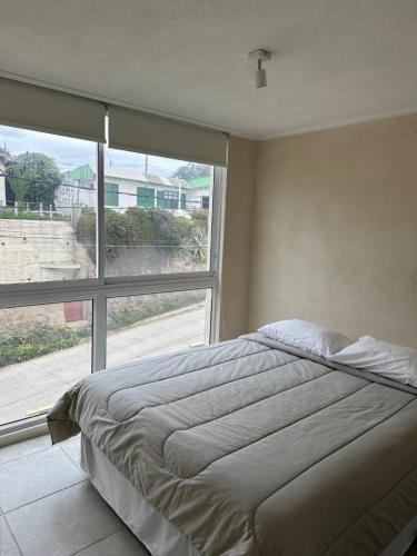 a bedroom with a bed and a large window at American Apart Hotel Los Vilos in Los Vilos