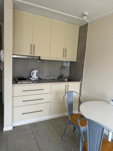a kitchen with white cabinets and a table with chairs at American Apart Hotel Los Vilos in Los Vilos
