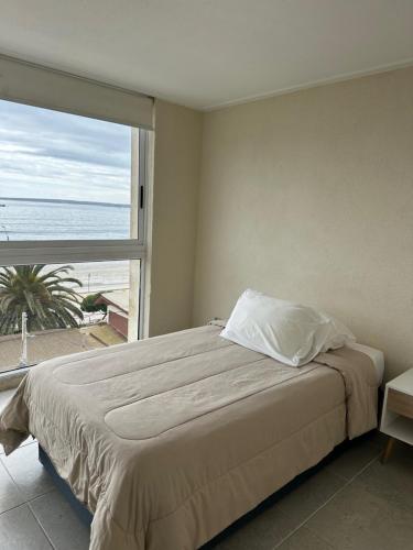 a bedroom with a bed with a view of the ocean at American Apart Hotel Los Vilos in Los Vilos
