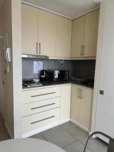 a kitchen with white cabinets and a black counter top at American Apart Hotel Los Vilos in Los Vilos