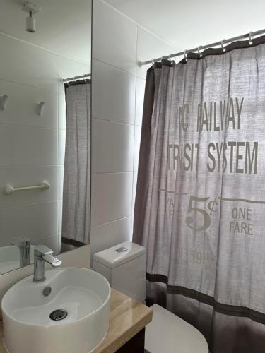 a bathroom with a sink and a shower curtain at American Apart Hotel Los Vilos in Los Vilos