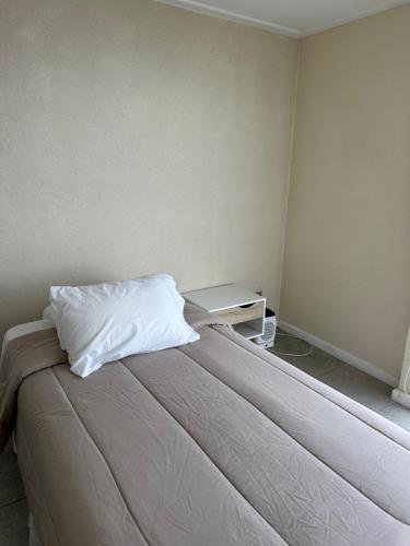 a bedroom with a bed with a white pillow on it at American Apart Hotel Los Vilos in Los Vilos