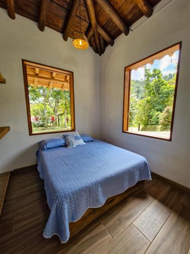 a bedroom with a bed and two windows at Caminos Alojamiento in Jardin