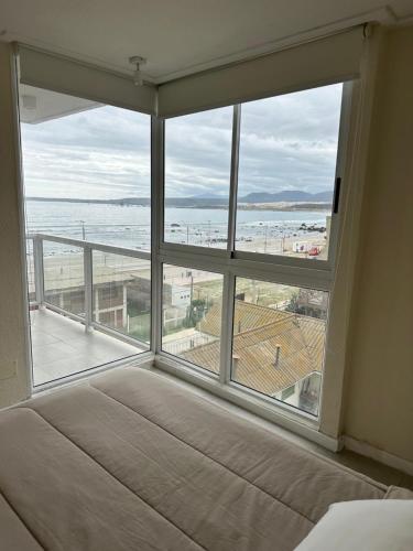 a bedroom with a large window with a view of the ocean at American Apart Hotel Los Vilos in Los Vilos