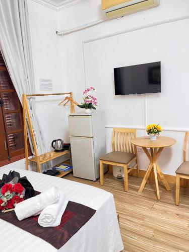 a room with a bed and a table and a tv at Okaeri Homestay in Hanoi