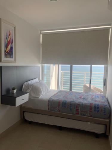 a bedroom with a bed with a large window at Radiante departamento frente al mar in Playas