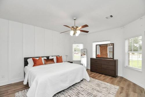 a white bedroom with a bed and a ceiling fan at 10min from Fort Bend Epicenter Stylish 4 Bedroom home in Lane Airpark