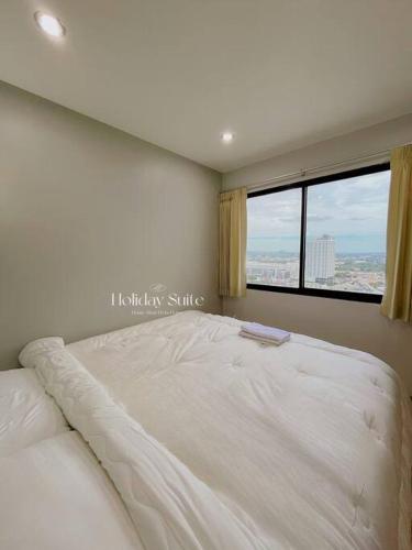 a white bed in a bedroom with a window at 2BR Holiday Suite Hat Yai in Hat Yai