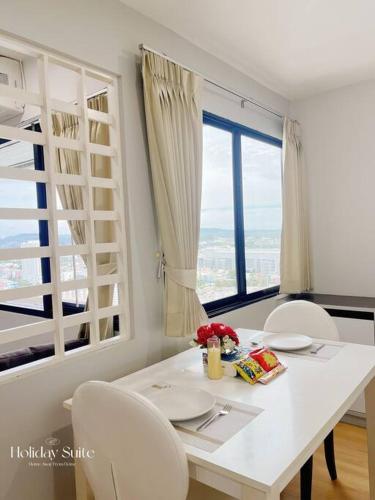 a white dining room table with white chairs and a large window at 2BR Holiday Suite Hat Yai in Hat Yai