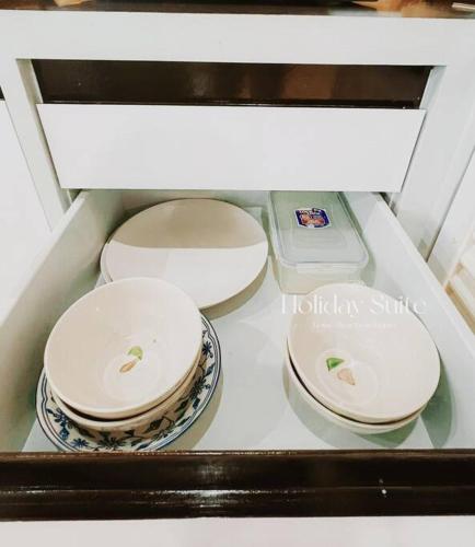 three bowls and plates sitting on a shelf in a drawer at 2BR Holiday Suite Hat Yai in Hat Yai