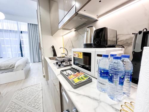 a kitchen with a microwave and bottles of water on a counter at EasyGo - Unbeatable Deals on Urban Rentals in Riviera 16 in Dubai