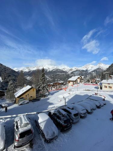 un grupo de autos estacionados en un estacionamiento cubierto de nieve en Panorama Valfréjus, en Modane