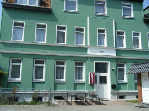 a green building with tables in front of it at Hotel & Pension Plagwitzer Hof in Leipzig