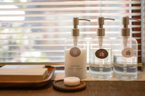 drei Glasflaschen auf einem Holztisch in der Unterkunft YSN Hill Breeze Retreat 云山南 玉龙雪山园林观景酒店 丽江古城束河白沙古镇店 in Lijiang