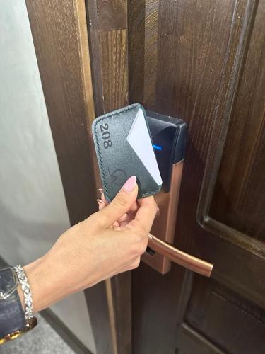 a person is unlocking a wooden door with a card at Grand Way Hotel in Taraz