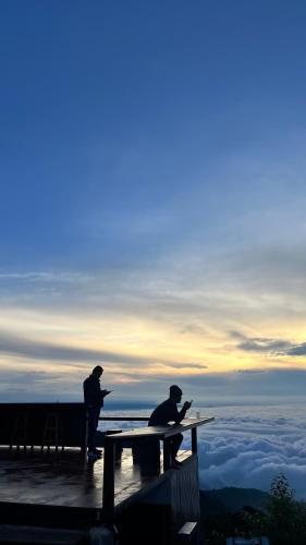 two men sitting at a table on top of the sky at วิมานหมอก ภูทับเบิก in Ban Maeo Thap Boek