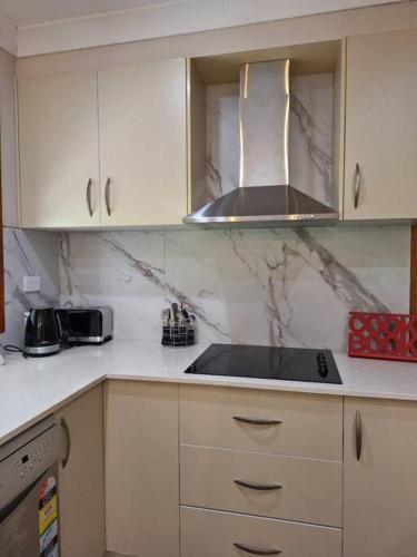 a kitchen with white cabinets and a stove top oven at Comfy 3 bed house in Ulladulla in Ulladulla