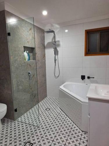 a bathroom with a shower and a tub and a toilet at Comfy 3 bed house in Ulladulla in Ulladulla