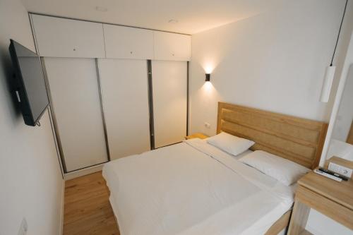 a small bedroom with a white bed and a desk at Marina Batumi Sea View in Batumi