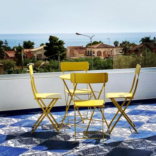 two yellow chairs and a table on a balcony at Le case di Fiò in Sciacca