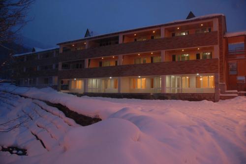 a building in the snow with a pile of snow at Tsaghkahovit Hotel in Tsaghkadzor