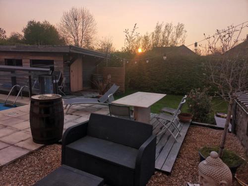 a patio with a table and chairs in a backyard at Gîte coquet 2 chambres, 2 salles de douches avec piscine, spa in Namur