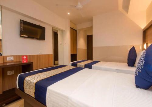 a hotel room with two beds and a flat screen tv at Hotel Mourya Residency in Navi Mumbai